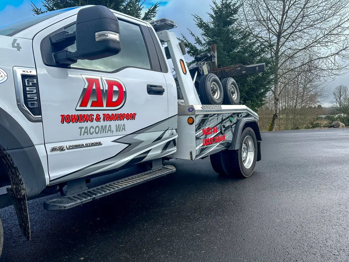 Close-up of a white Ford F-550 tow truck with red and gray AD Towing & Transport door lettering and side graphics