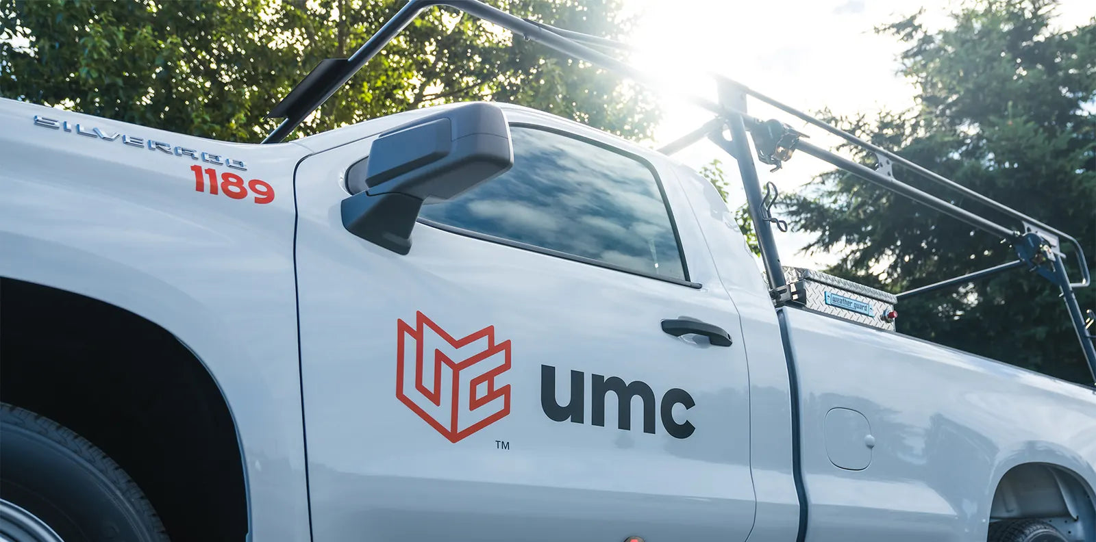 Close-up of a large UMC logo and truck number lettering on the door of a white Chevrolet Silverado work truck